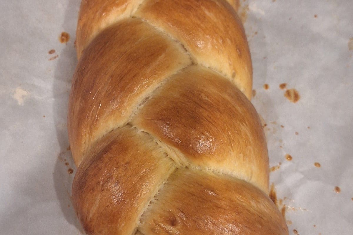 A golden challah braid resting on parchment