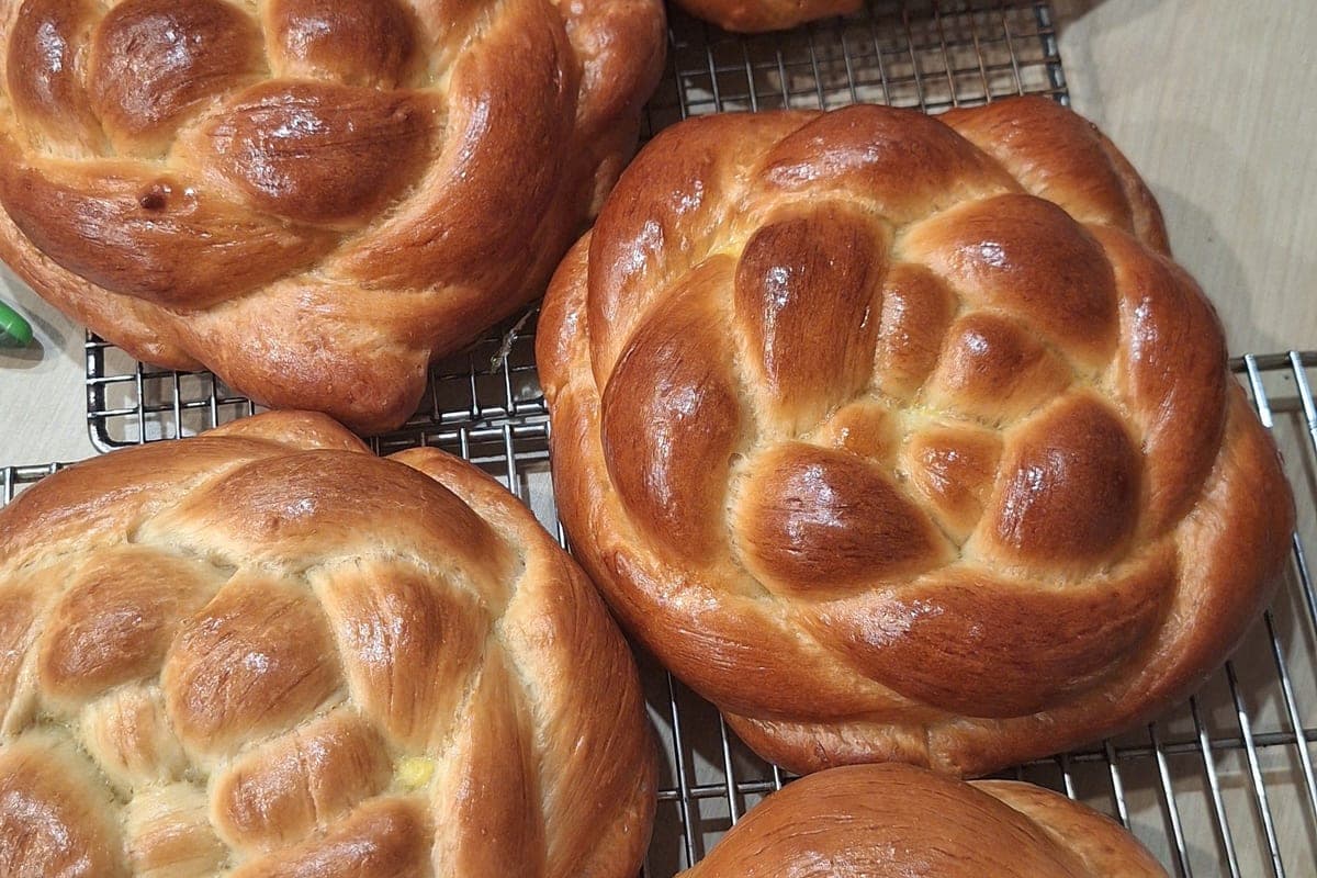 Several round challahs cooling on a wire rack